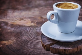 Close up view white coffee cup with capuchino on vintage wood cross cutted tree trunk