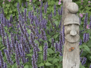 Wooden sculpture surrounded by lavender with butterfly in blooming garden, papenburg, germany