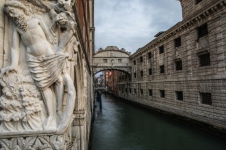 Stone sculpture of an ancient deity, Bridge of Sighs or Ponte dei Sospiri at the Doge's Palace over