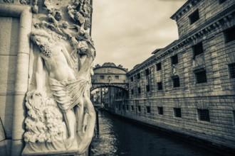 Stone sculpture of an ancient deity, Bridge of Sighs or Ponte dei Sospiri at the Doge's Palace over