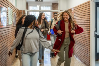 Cheerful diverse university students running joyfully through the school hallway after class,