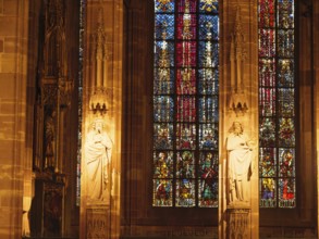 Statues in a cathedral, flanked by colourful stained glass windows, strasbourg, france