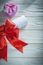 Paper roll with red bow metal present box on wooden board holidays concept