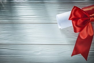 Paper roll with red ribbon on wooden board copy space