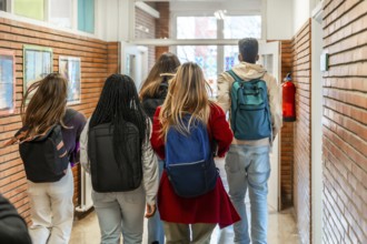 Diverse group of high school students walking together down a bustling school hallway after class,