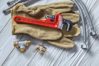 Adjustable tensioner on leather gloves pipe fixtures water hoses on white wood boards