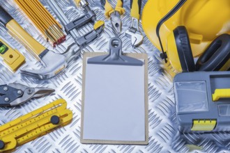 Clipboard with white sheet of paper and set construction tools