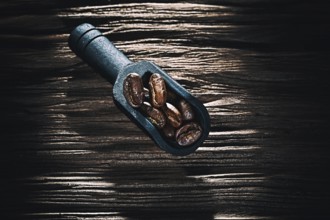 Black coffee grains in scoop on vintage wooden board