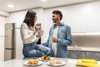 Young couple sharing a moment together while having breakfast and coffee in their modern kitchen