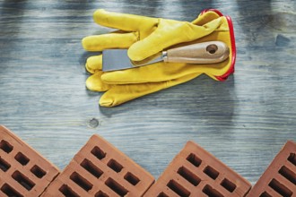 Assortment of red construction bricks leather safety gloves palette knife building concept