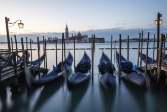 Morning light in front of sunrise, Venetian gondolas, boat dock at St Mark's Square, church of San