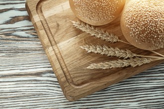 Chopping board bread wheat ears on wooden surface