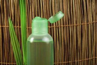 Green cosmetic bottle and green leaf. Copy space