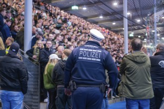 Police officer monitors a dense crowd in a sports hall, Heilbronner Falken Vs Bietigheimer