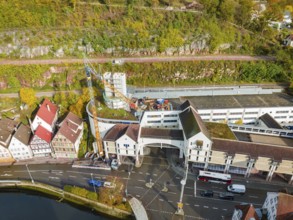 Urban area with construction site next to a river, red roofs and autumnal trees, extension of the