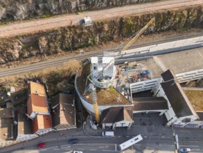 Bird's eye view of industrial construction site with crane and buildings next to railway lines,