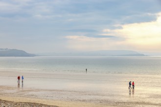 People walking on the sandy beach by the sea in a beautiful morning light, Crozon peninsula,