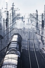 Deutsche Bahn AG tracks backlit with goods train. Overhead line, signals and infrastructure.