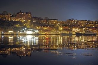 Night city view with illuminated buildings and reflections in the water, winter, ice, capital city,