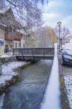 Small river flowing under a bridge in a snowy town, Aidlingen, Böblingen district, Germany, Europe