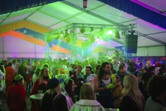 People dancing and celebrating at an event with colourful lighting, carnival, Schlagerkuchen