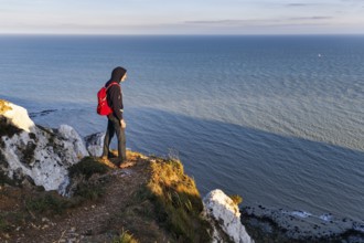 Hiker enjoying views of cliffs, chalk coast, Beachy Head, Eastbourne, South Downs, Sussex, England,