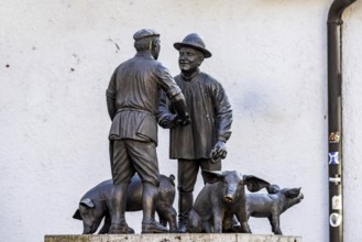 Butcher and farmer haggle over the price of a pig. Statue group in memory of the Ulm mule market.