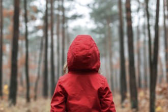 Back view of young girl in red coat in forest. Generative AI, AI generated