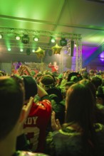 Energetic concert scene with a dense crowd and green-lit stage, carnival, Schlagerkuchen Donzdorf,