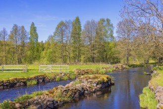 Water canal with stone piers in a beautiful rural landscape with green meadows and lush trees