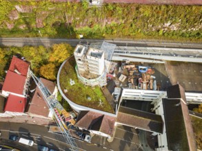 Aerial photo of a construction project with a concrete tower and surrounding streets and autumnal