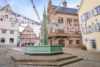 Historic square with green fountain and colourful pennants surrounded by old and half-timbered