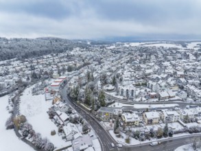 Snowy settlement from the air with trees and winding streets under a cloudy sky, Aidlingen,