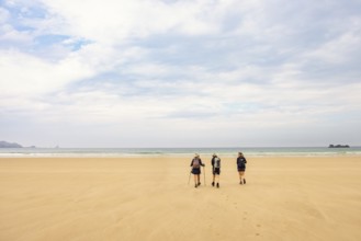 Women walking to the sea on a sand beach with a view to the horizon, Crozon peninsula, Bretagne,