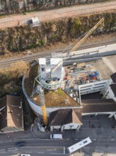 Roof and construction crane over a round building, surrounded by urban infrastructure, extension of