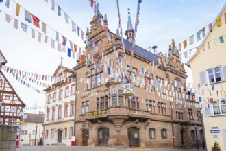 Historic building with colourful pennants and clock, surrounded by half-timbered houses, Meßkirch,