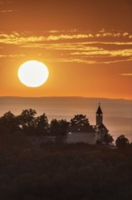 Teck Castle in front of a dramatic orange sunset on a hill, near Kirchheim unter Teck, Swabian Alb,