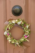 Detail of an antiquated front door with floral wreath in a building on the Krämerbrücke in the