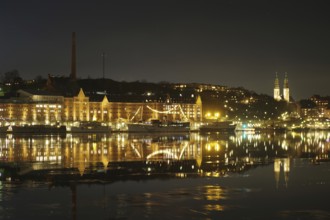 Shore view at night with illuminated buildings, ships and church towers, winter, ice, capital,