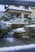 Snow-covered house with a small river in the garden, Aidlingen, Böblingen district, Germany, Europe