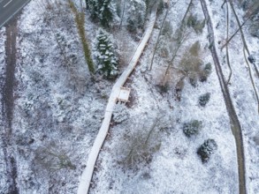 Bird's eye view of a snowy forest path with a road nearby, New wooden footbridge in Calw city