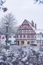 A snow-covered half-timbered house in a picturesque street in winter, Aidlingen, Böblingen