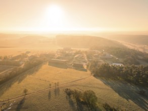 A village in the morning light, surrounded by fields and with a light fog for a peaceful