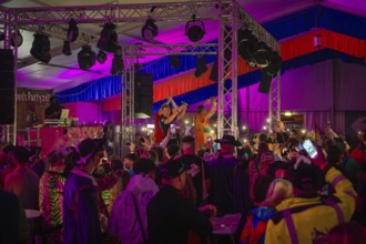 Zipfelbuben, people celebrating at a concert in a decorated tent with colourful lights, carnival,