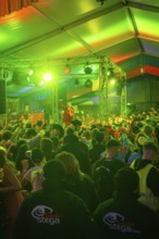 Concert atmosphere with green lights and an energetic audience in front of the stage, carnival,