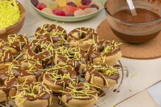 Donuts decorated with chocolate and sprinkles, colourful sweets in the background