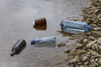 Environmental pollution, Household waste washed up on the lake shore, Plastic and glass bottles,