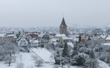 Snow-covered village with striking church tower under a quiet winter blanket, Korb-Steinreinach,