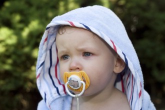 One-year-old boy with bathrobe, baby with dummy, teat