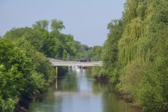 Road bridge with cyclist and car over the river Wümme in spring, Lower Saxony, Germany, Europe